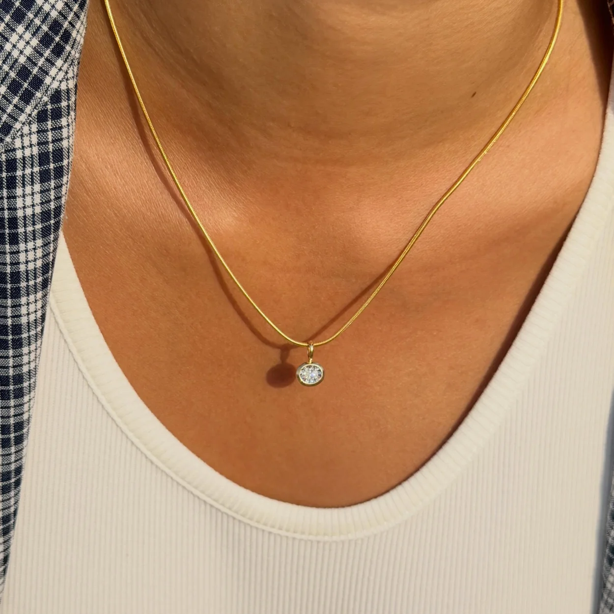 Monica Vinader gold pendant necklace worn with a white top