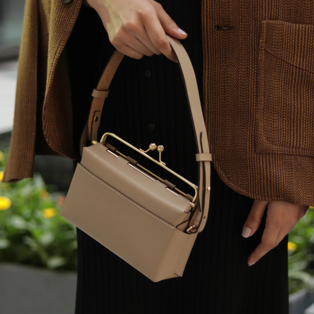 Nappa Dori cream leather top-handle bag worn with a corduroy jacket