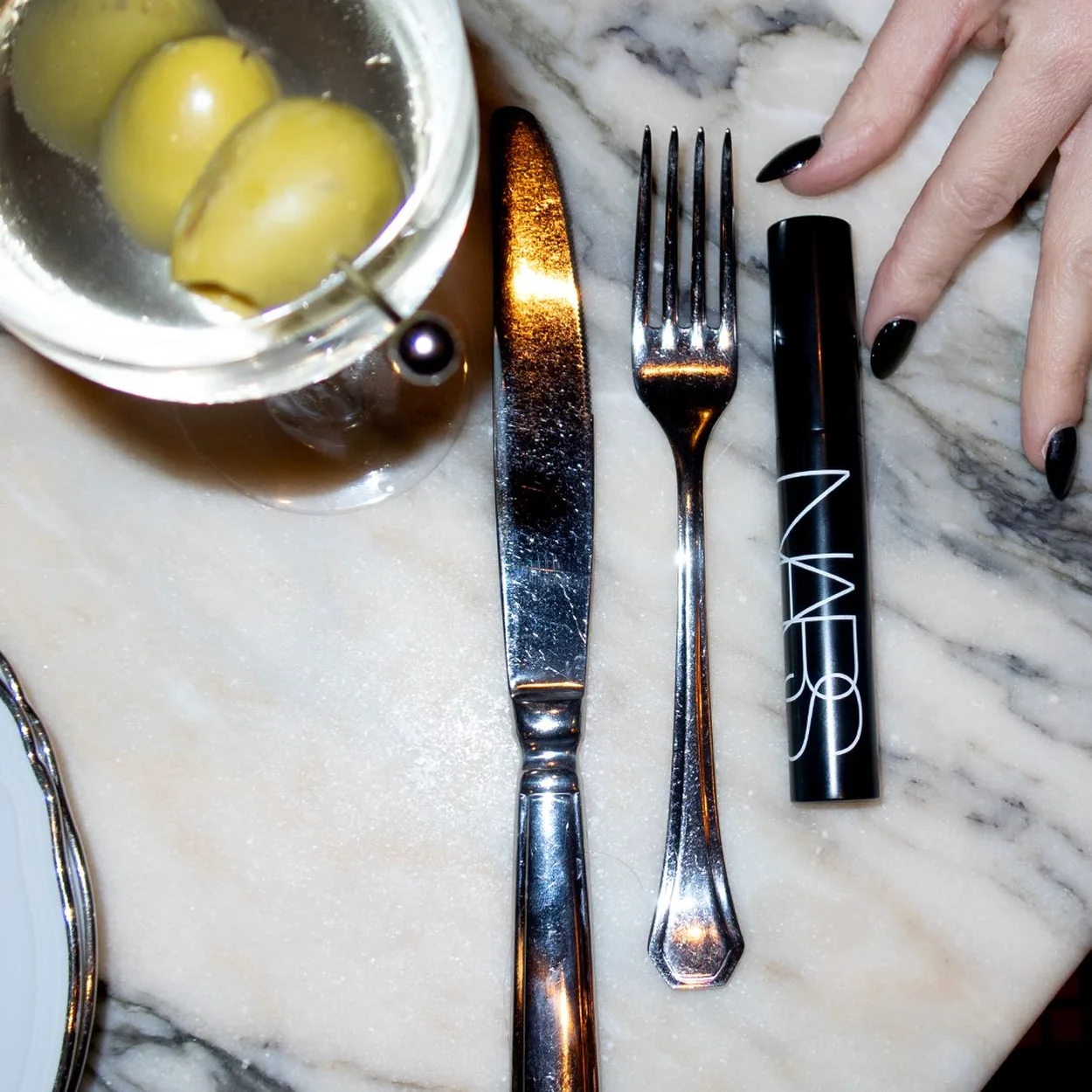 NARS mascara on a marble table beside a martini glass