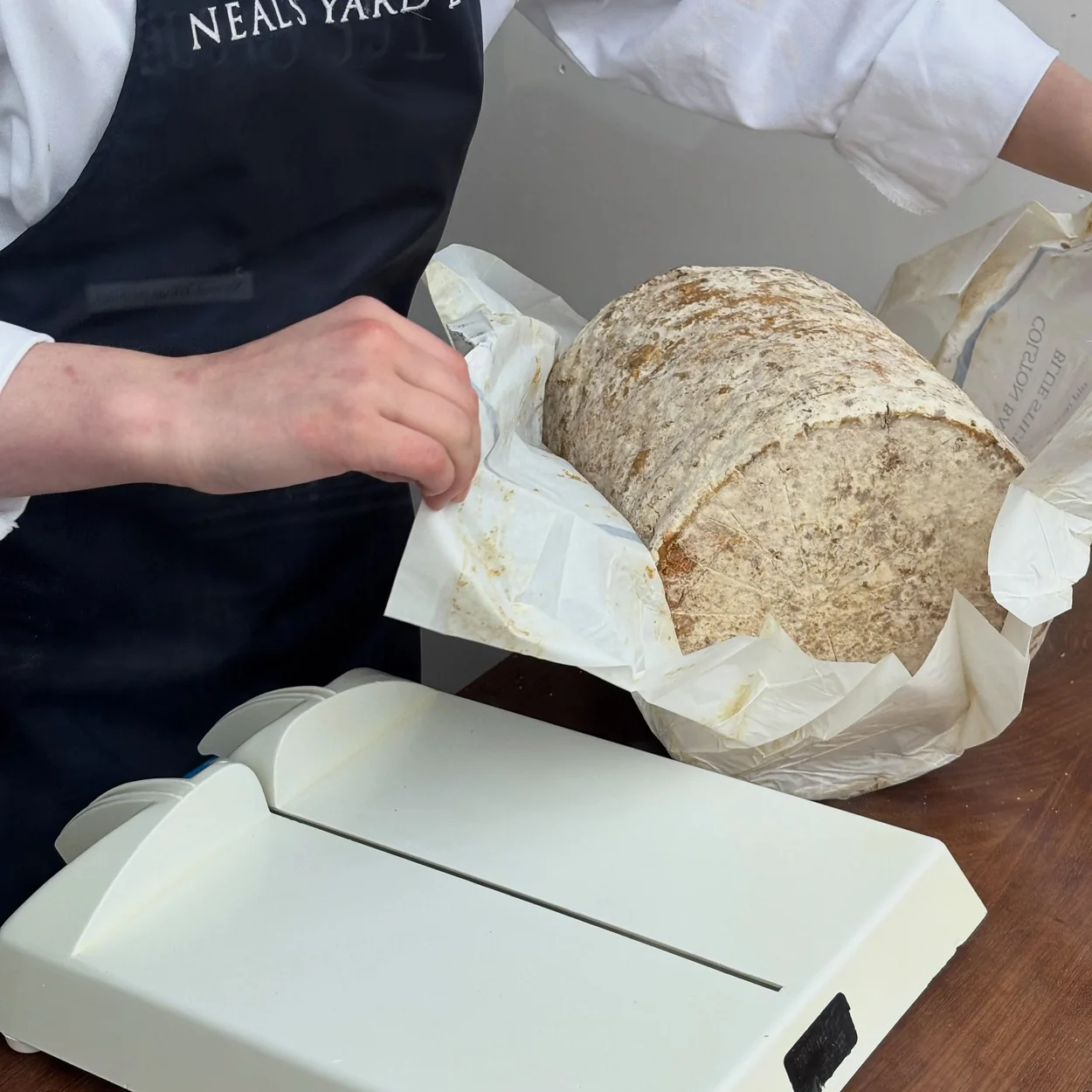 Neal's Yard Dairy staff wrapping a whole cheese in paper