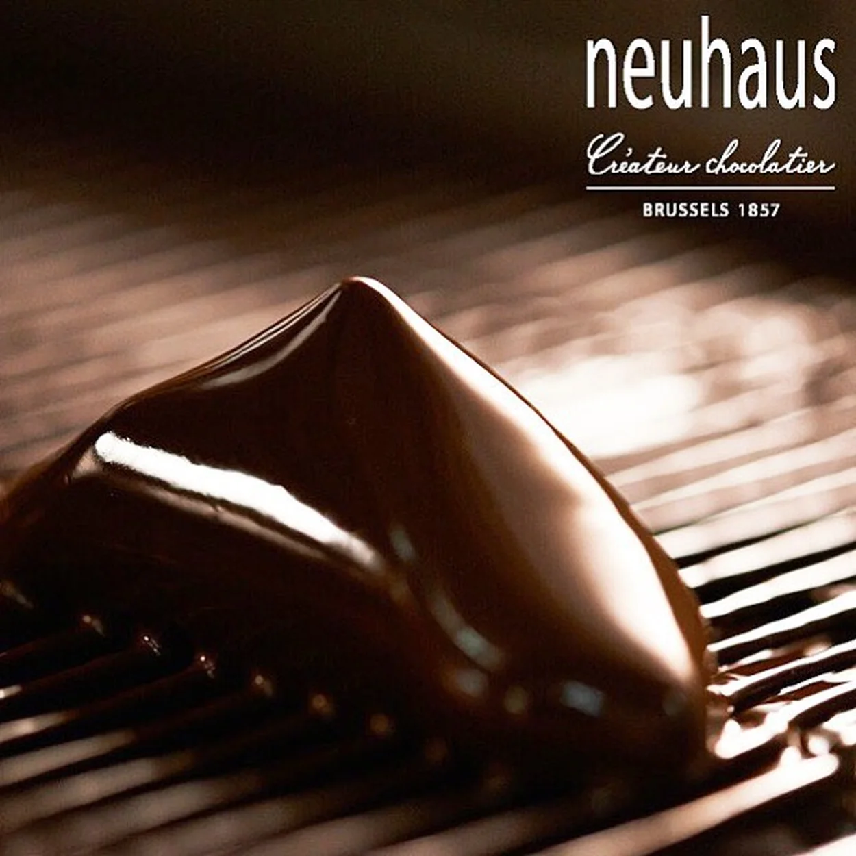 Neuhaus dark chocolate praline being coated on a rack