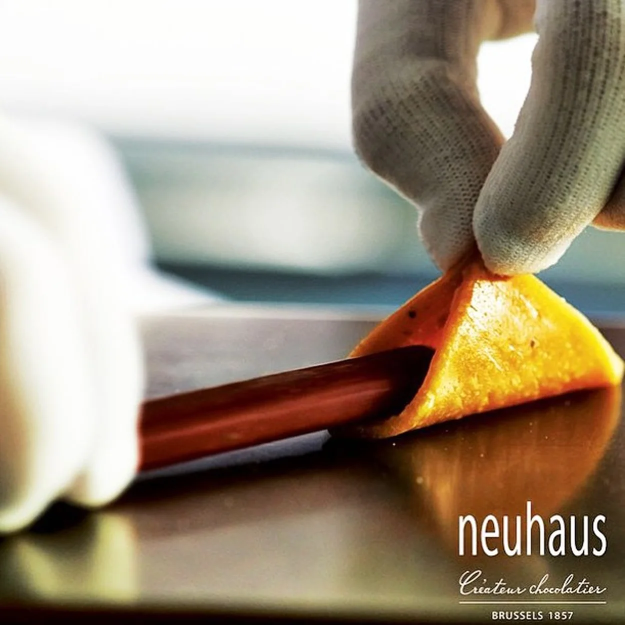 Neuhaus chocolatier dipping candied orange peel in chocolate