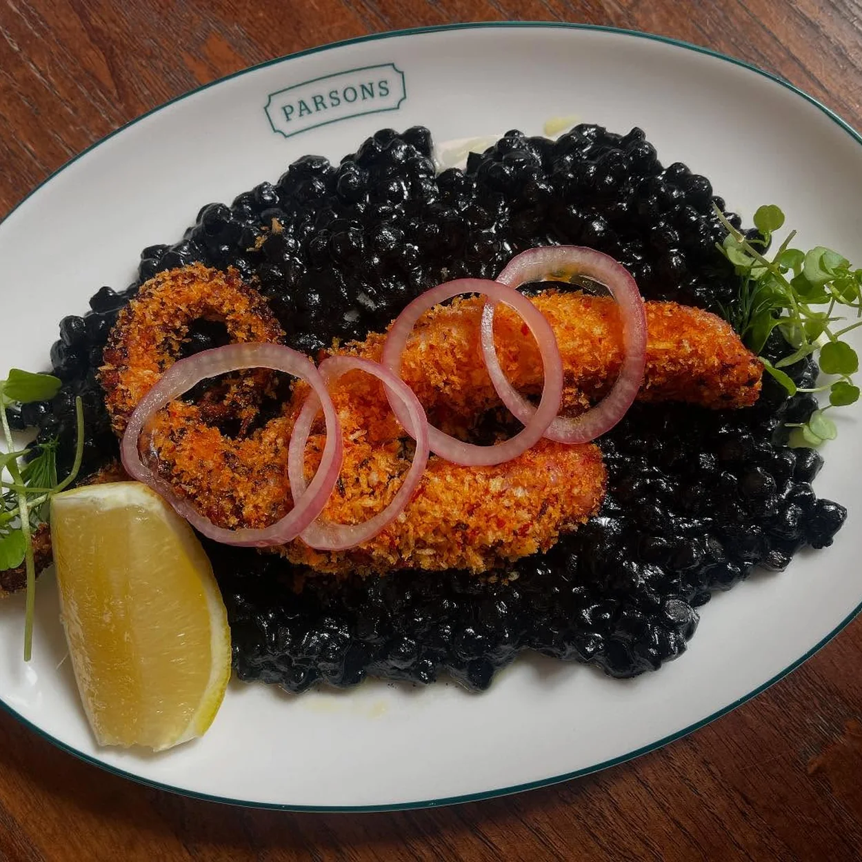 Parsons crumbed fish on squid ink rice with lemon