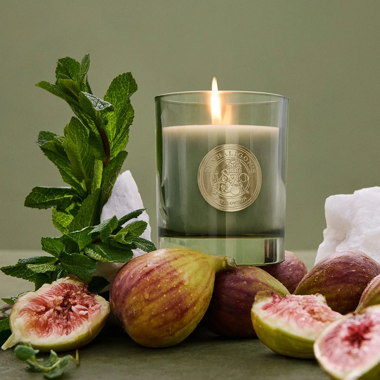 Penhaligon's scented candle beside fresh figs and mint