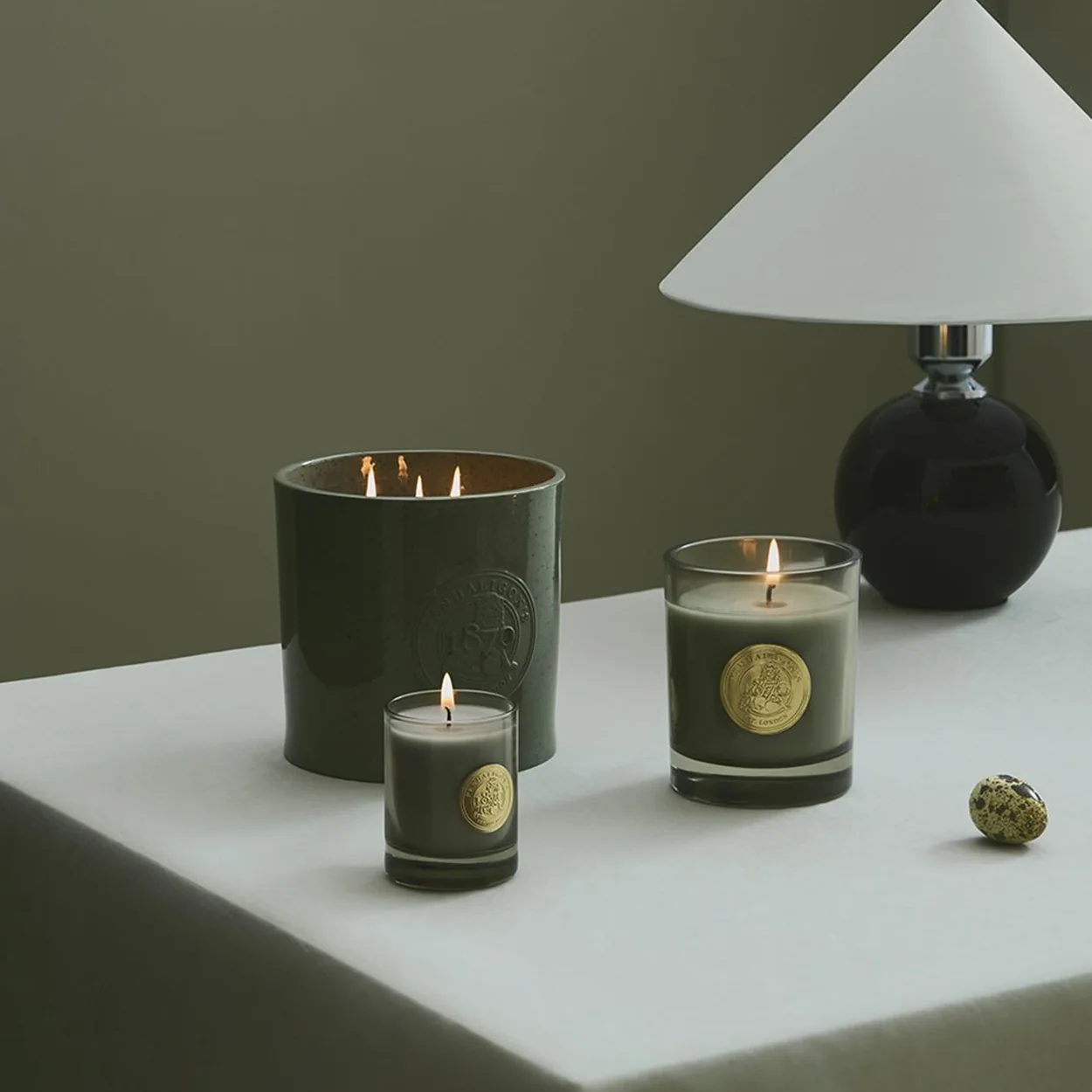 Penhaligon's scented candles in green glass on a bedside table
