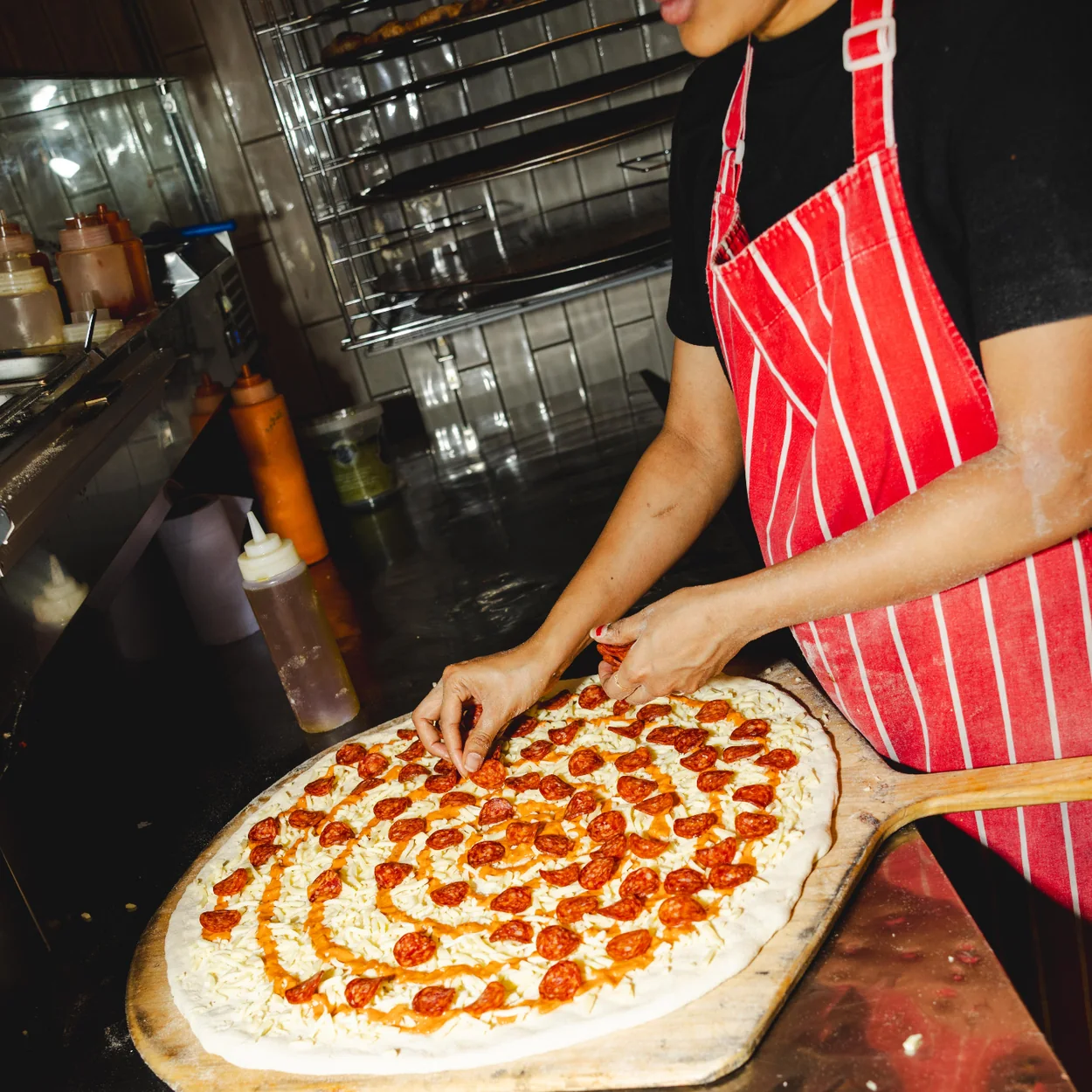 Seven Dials Market trader preparing a pepperoni pizza at a stall