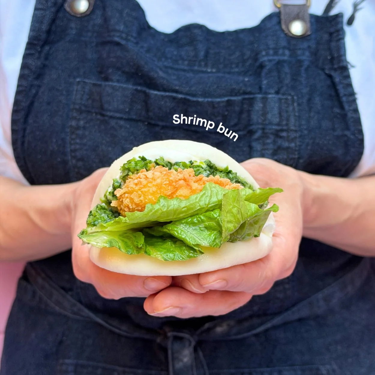 Seven Dials Market shrimp bao bun held by a trader in an apron
