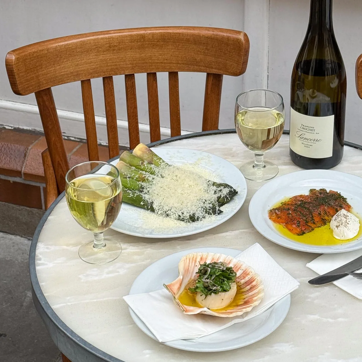 St. JOHN bistro table with white wine and plates of seafood