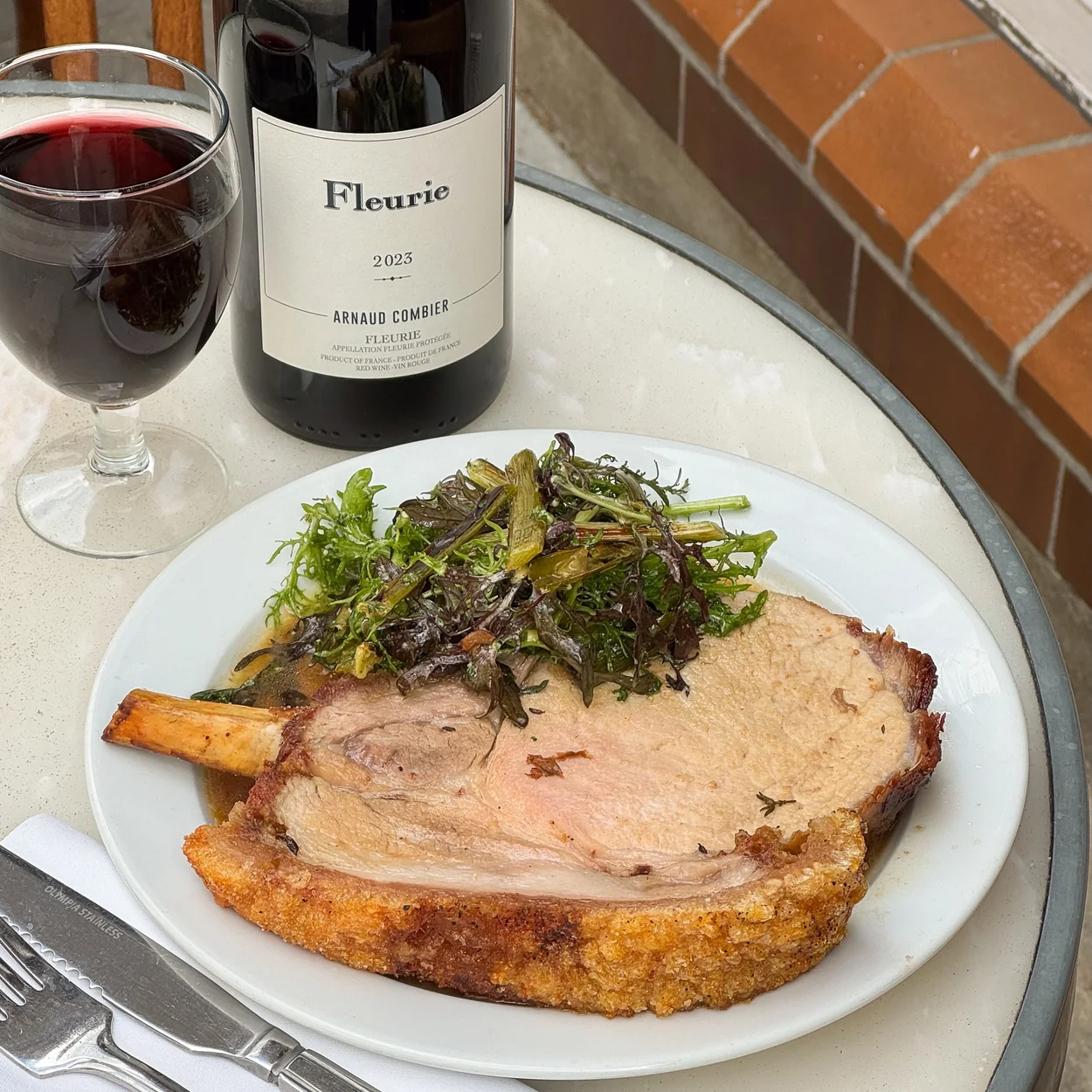 St. JOHN roast pork chop with greens and a glass of Fleurie