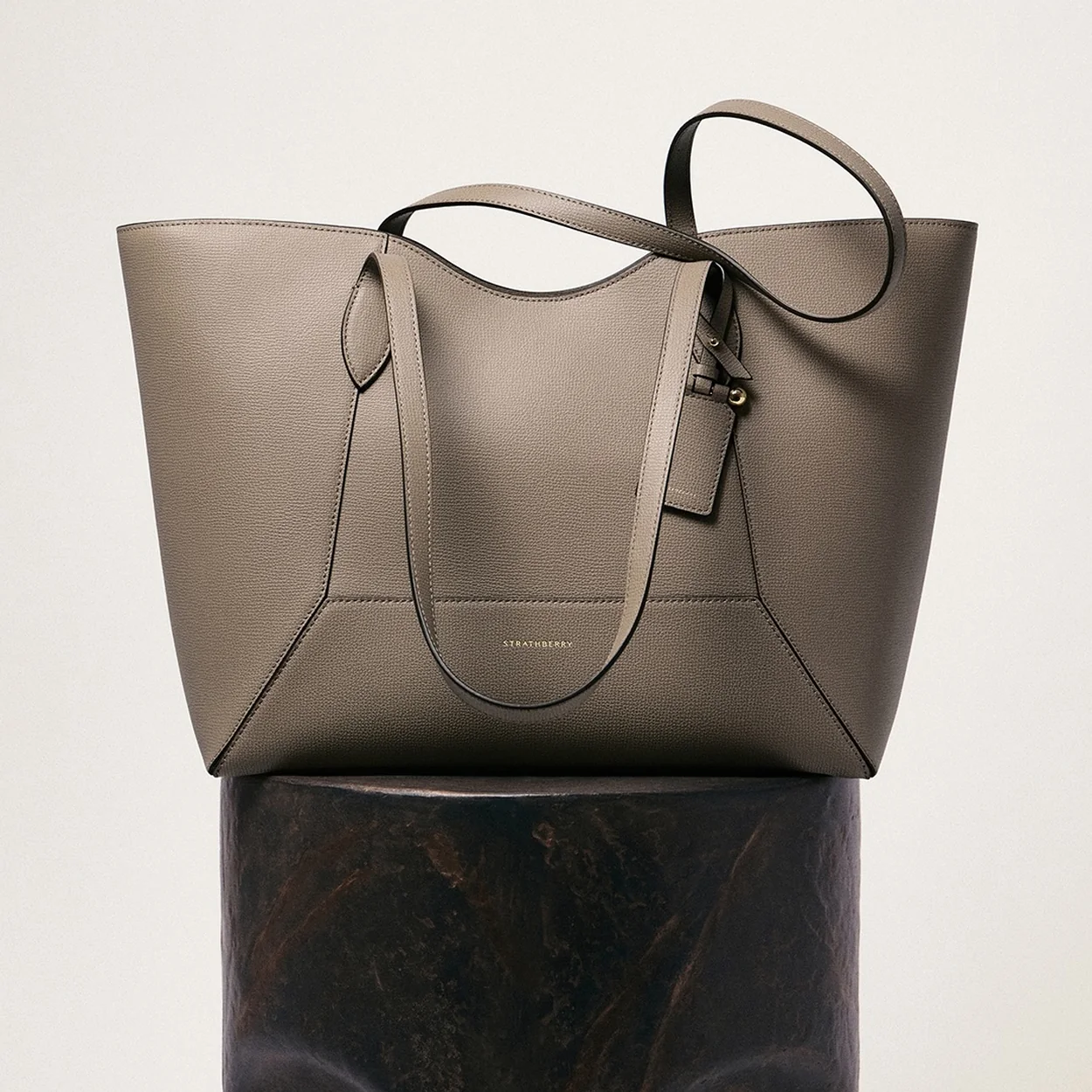Strathberry grey leather tote on a stone plinth