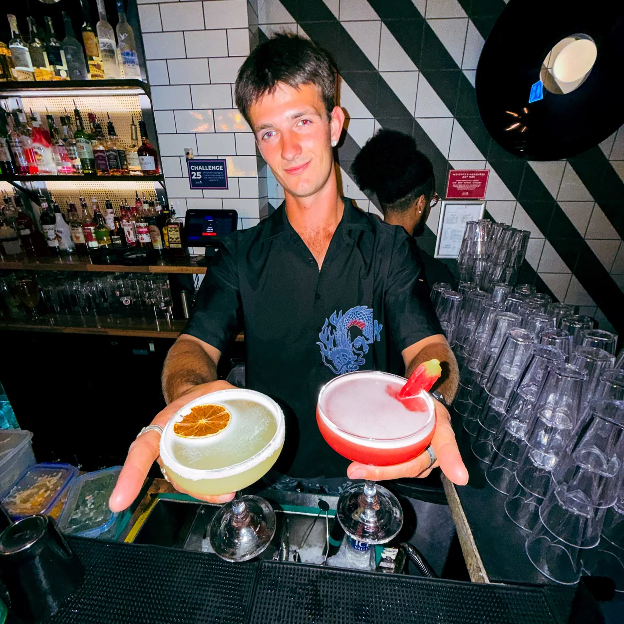 Tequila Mockingbird bartender serving two cocktails at the bar