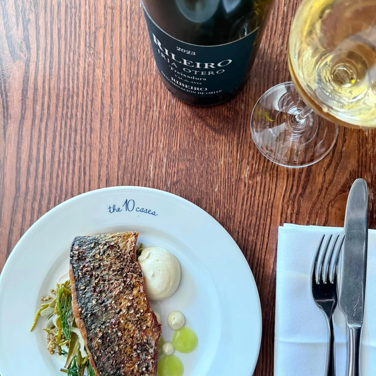 The 10 Cases grilled fish dish served with a glass of white wine