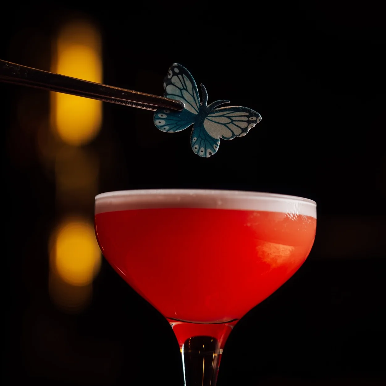 The Escapologist red cocktail with a butterfly garnish in the candlelit bar