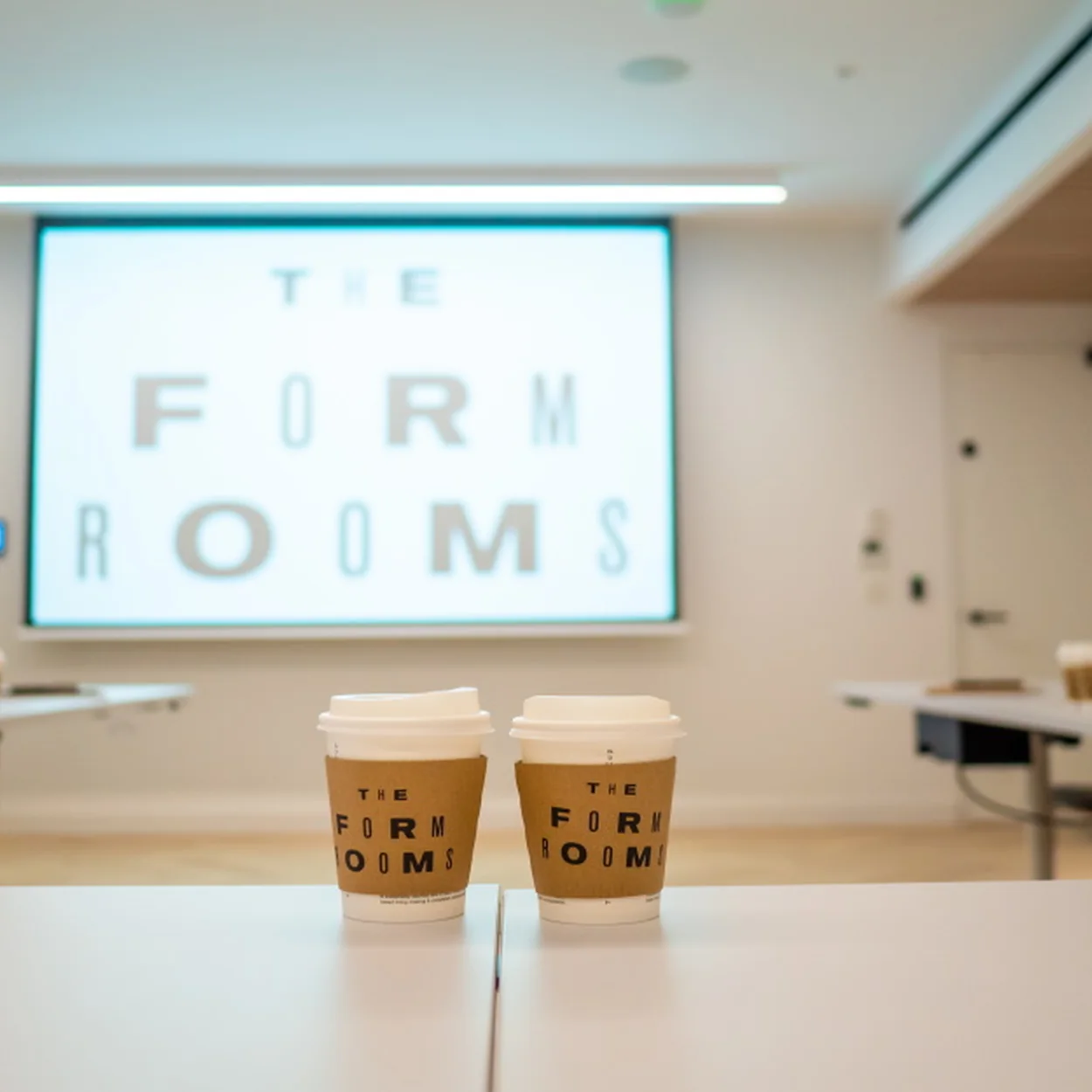 The Form Rooms meeting room with branded coffee cups and screen