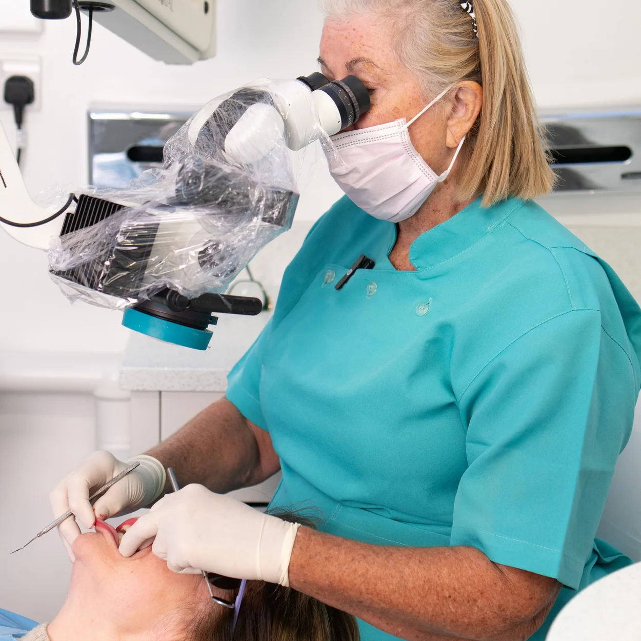 The Gentle Dentist clinician treating a patient under a dental microscope