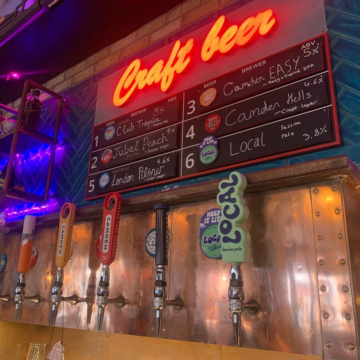 The Long Acre craft beer taps under neon lighting