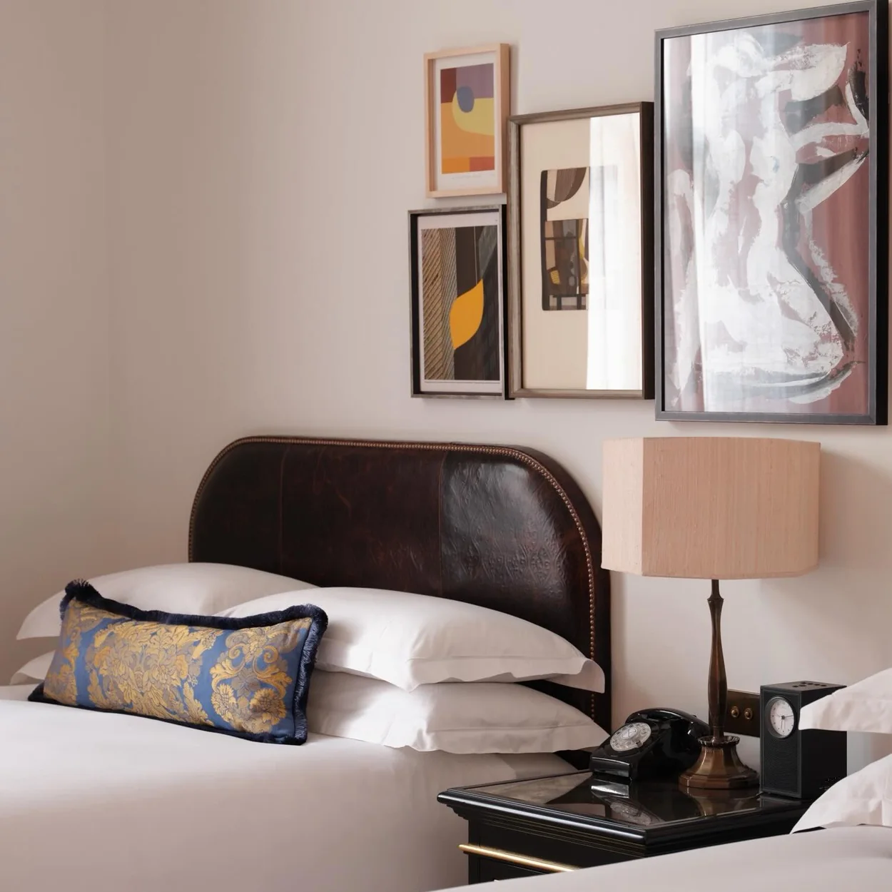 NoMad London bedroom with leather headboard and framed art