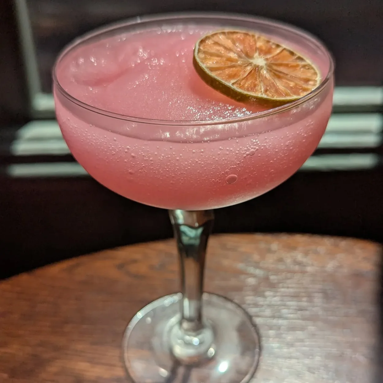 The Round House pink cocktail with a dried citrus garnish