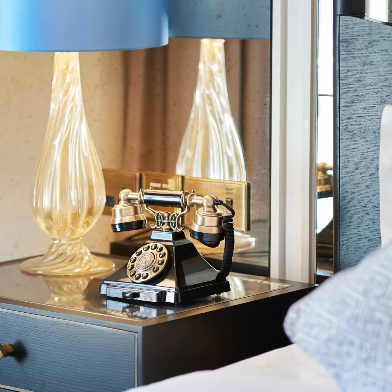 The Waldorf Hilton bedroom detail with bedside lamp and vintage-style telephone