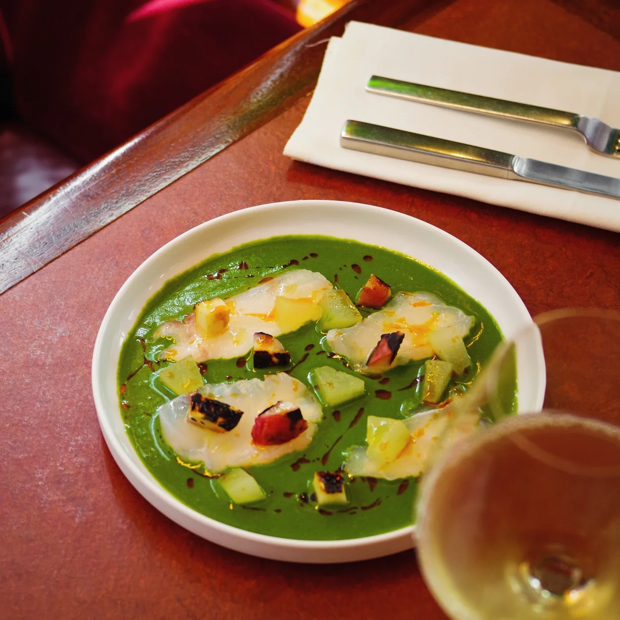 Town restaurant crudo in green herb sauce with a glass of wine