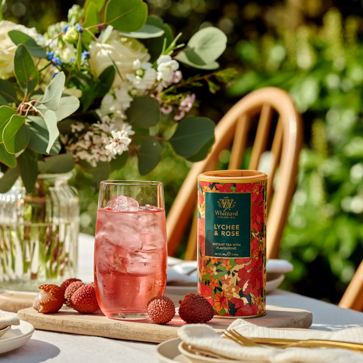 Whittard of Chelsea Lychee and Rose tea tin with iced tea on a garden table
