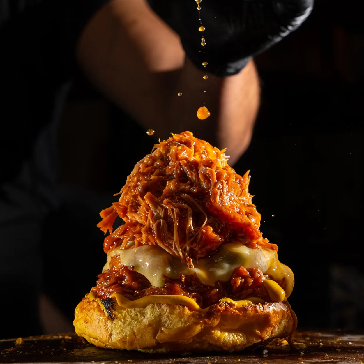 Piled shredded meat and cheese being finished by a member of staff at Dirty Bagels