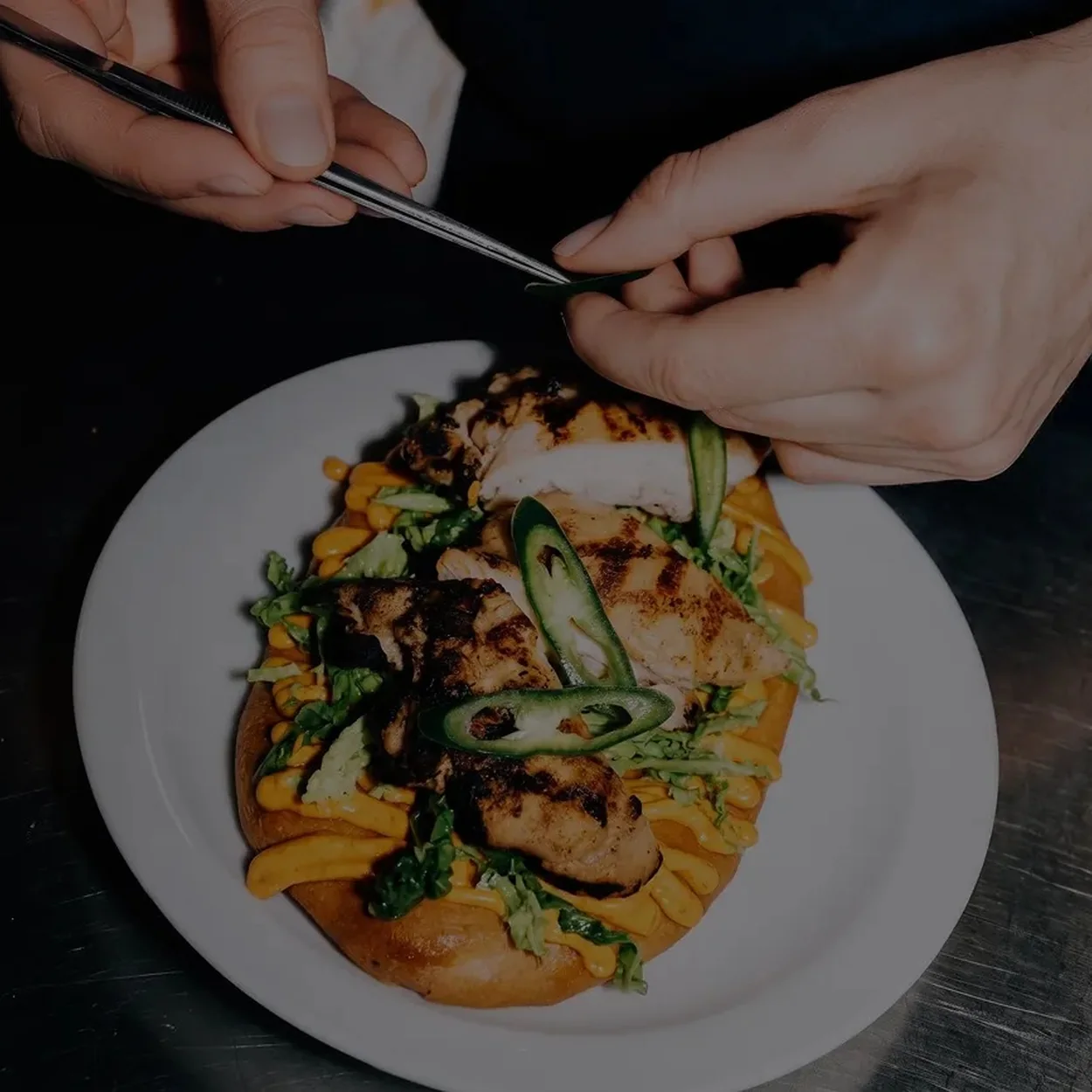 Flatbread kebab plated with herbs and greens being cut with a knife and fork