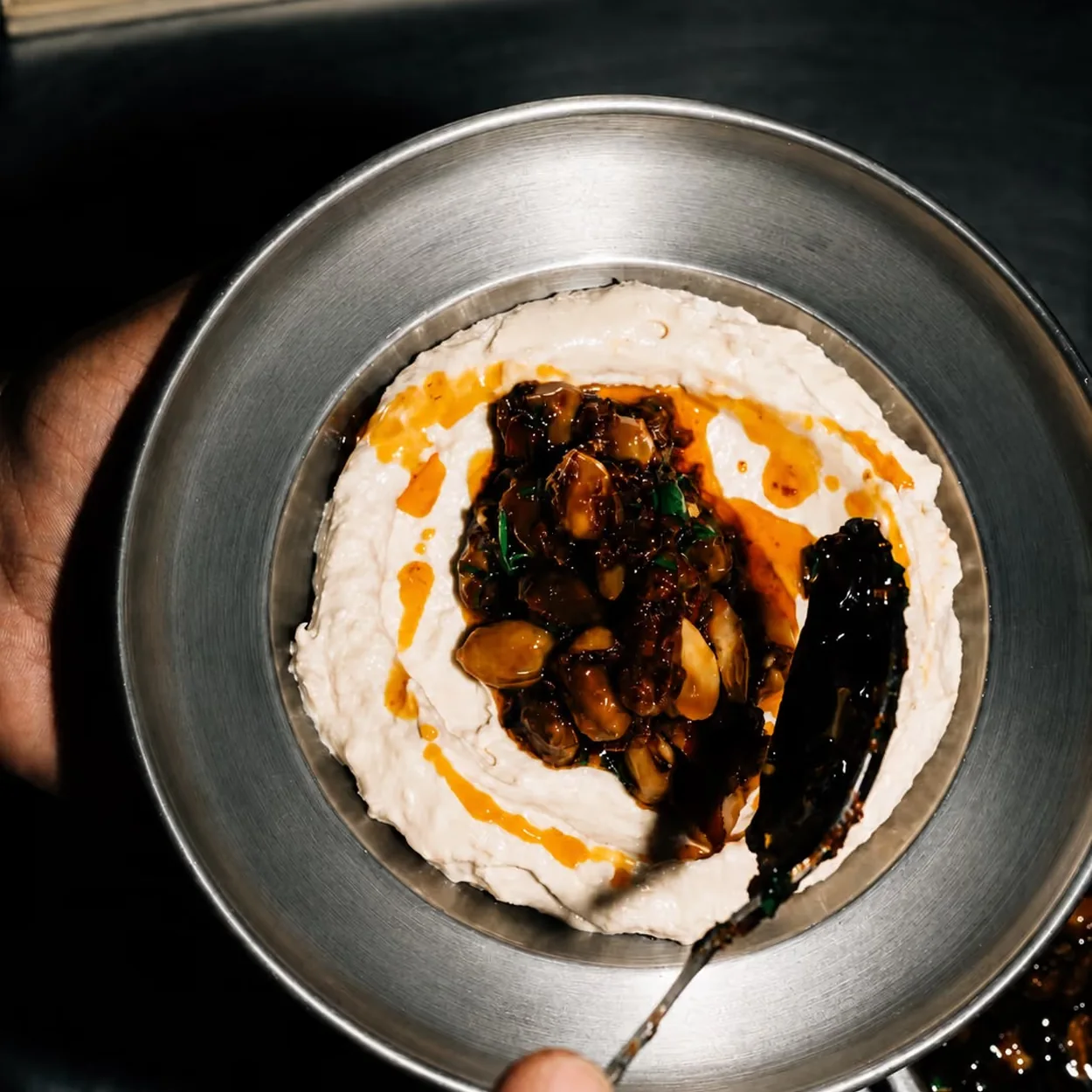 Whipped dip topped with spiced meat and chilli oil served in a steel dish